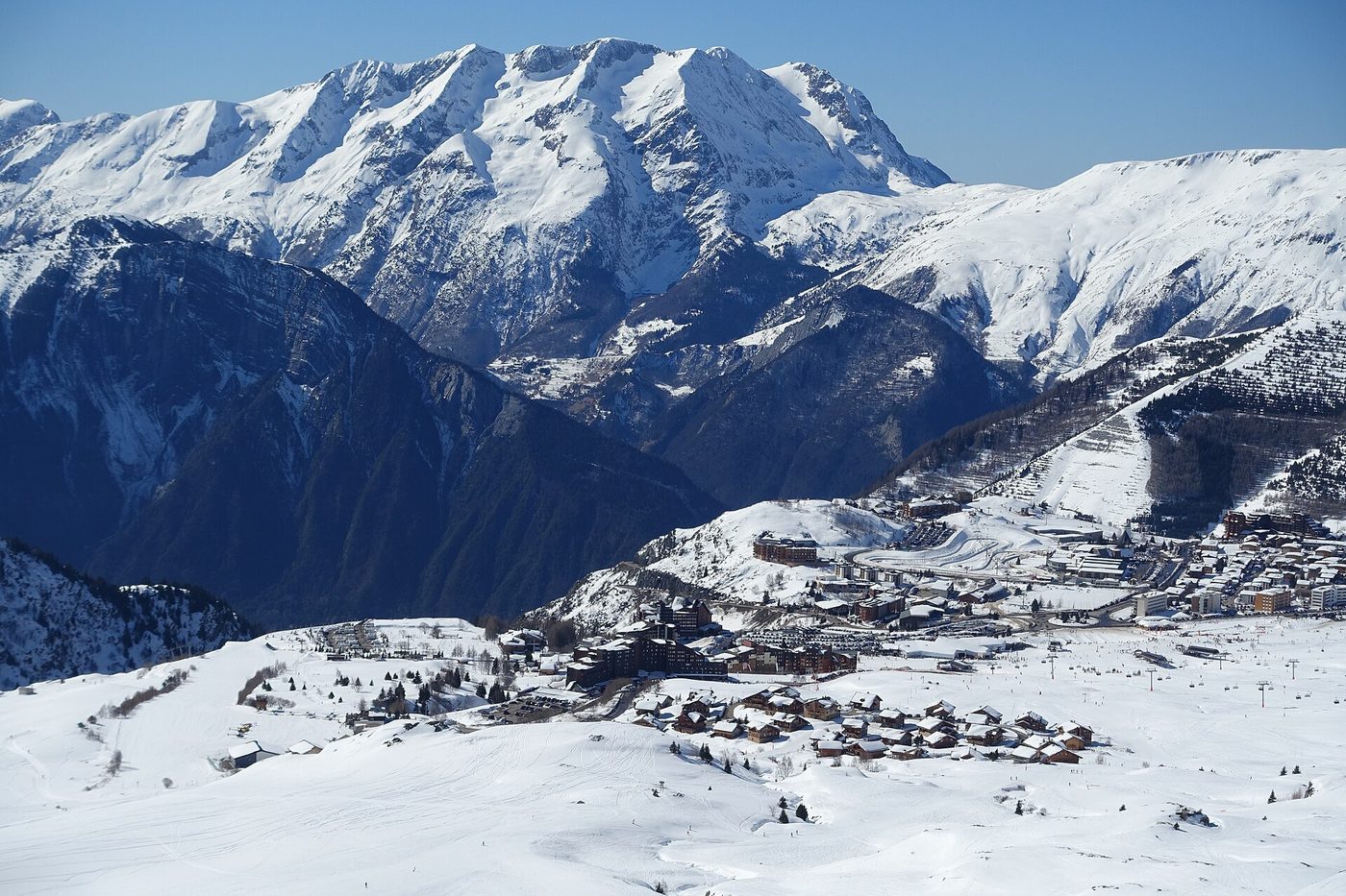 Aerial view of Alpe d’Huez ski resort village with snow-covered slopes and mountain backdrop