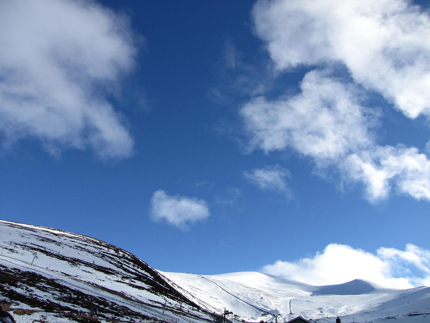 The Cairngorm Mountain ski area in winter with snow-covered slopes, chairlifts and the Cairngorm summit plateau