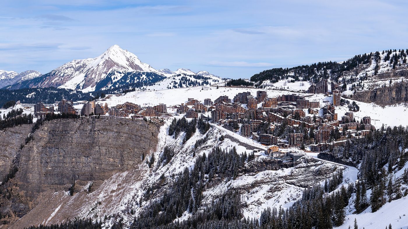 The timber-clad resort of Avoriaz perched dramatically on a snowy cliff with Alpine peaks behind