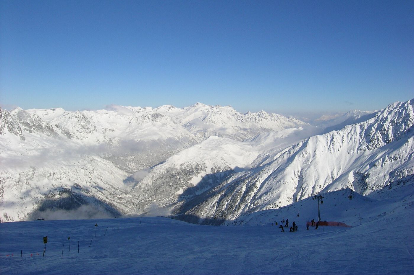 Skiers descending a snowy piste high above the Chamonix valley with peaks all around
