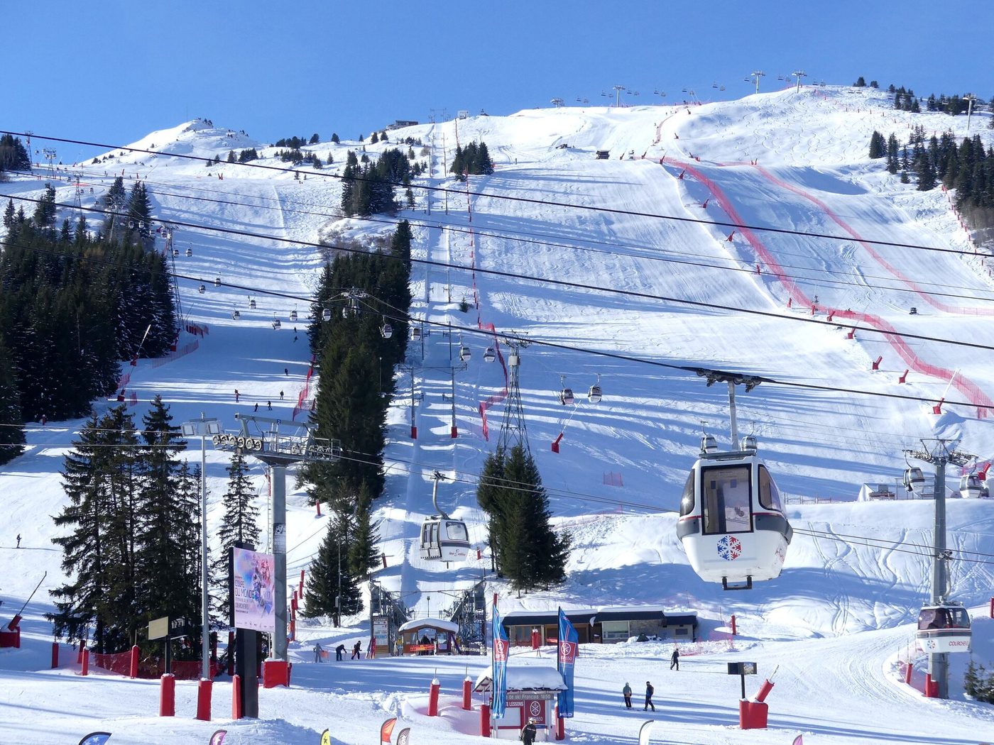 Wide ski pistes on the Loze side of Courchevel with a gondola cabin and snow-laden trees in winter