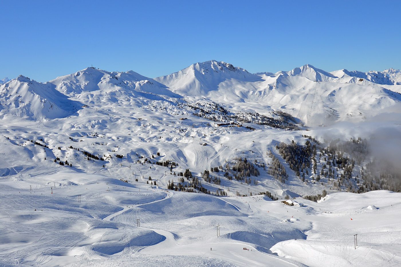 La Plagne ski resort with a chairlift in the foreground and the snowy mountain backdrop of the French Alps