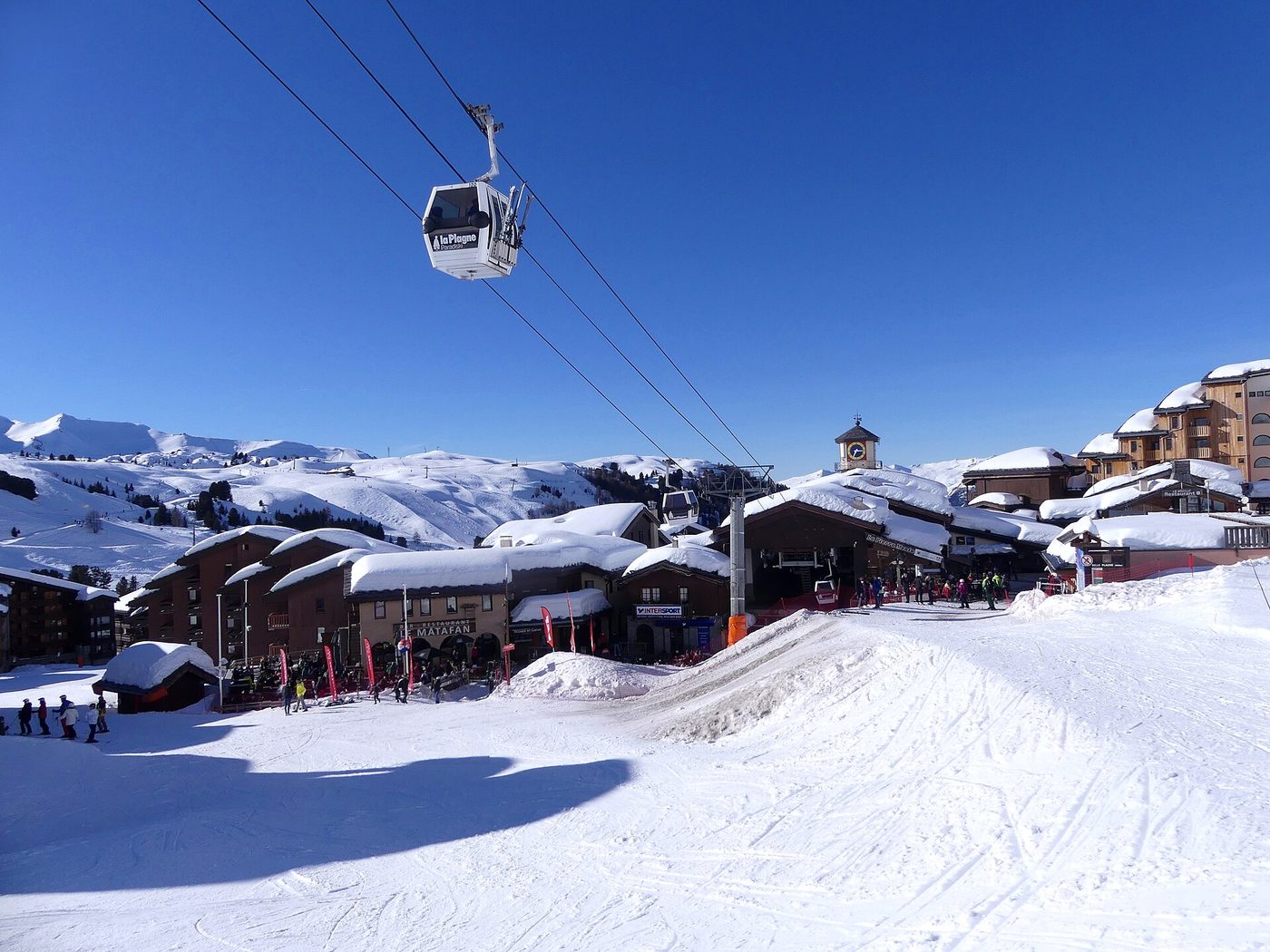 The resort village of Belle-Plagne in La Plagne in winter with a gondola cabin visible against blue sky