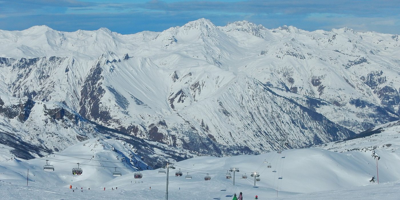 Wide panorama of the Les Trois Vallées ski domain with chairlifts, groomed pistes and skiers visible across a vast snowy alpine landscape