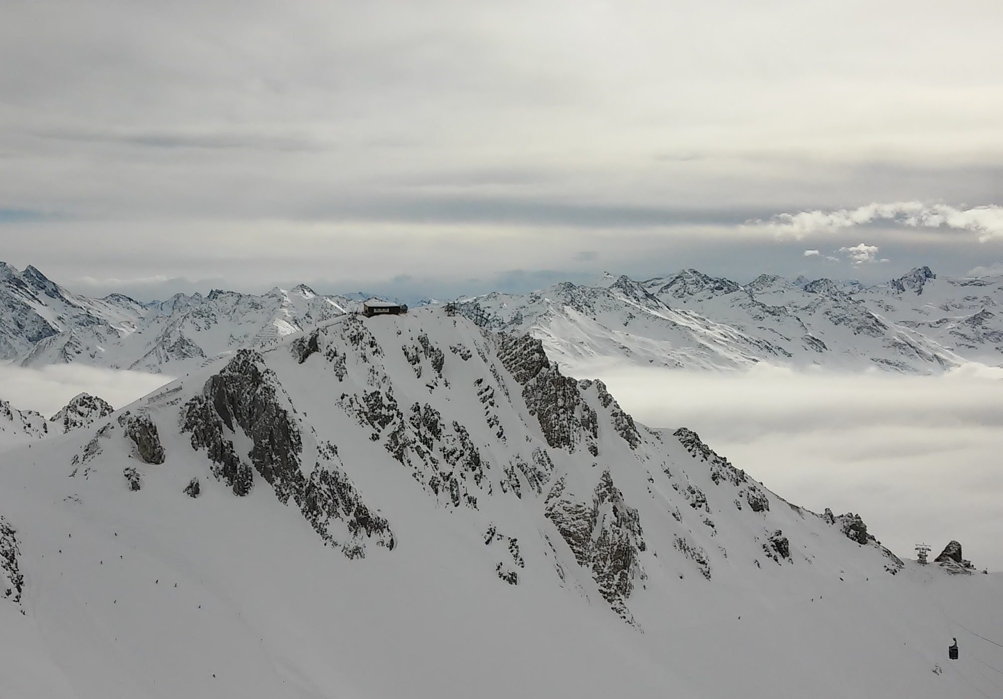 Winter view from the Valluga cable car top station over the snow-covered Schindlergrat ridge and Schindler couloirs above a sea of clouds at St. Anton am Arlberg
