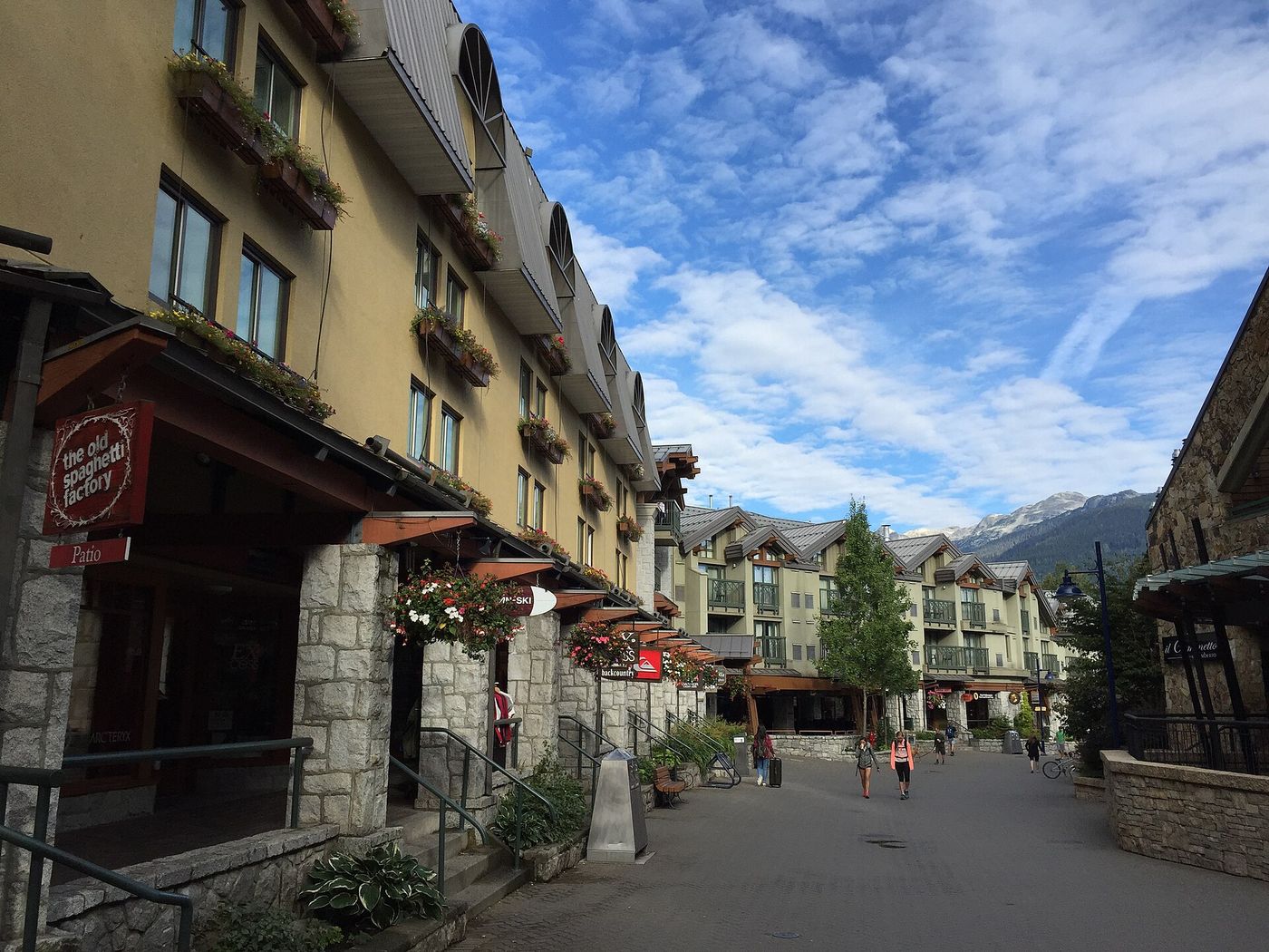The car-free pedestrian stroll through Whistler Village lined with shops and restaurants beneath snowy mountains